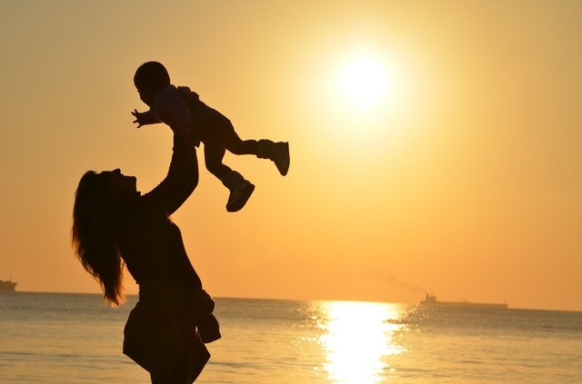 woman-carrying-baby-at-beach-during-sunset-51953